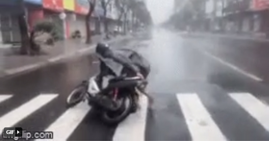 Gió bão quật muốn “nhấc người”, nam thanh niên gồng mình dắt xe vào lề đường ở Đà Nẵng